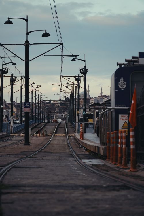 Free Tram tracks on an overcast day leading towards a historic cityscape with architectural landmarks. Stock Photo