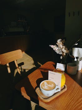 Warm cafe ambiance with latte and flowers in natural light.