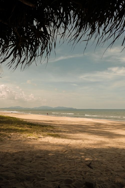 Free A peaceful beachscape with distant mountains under a clear sky. Stock Photo