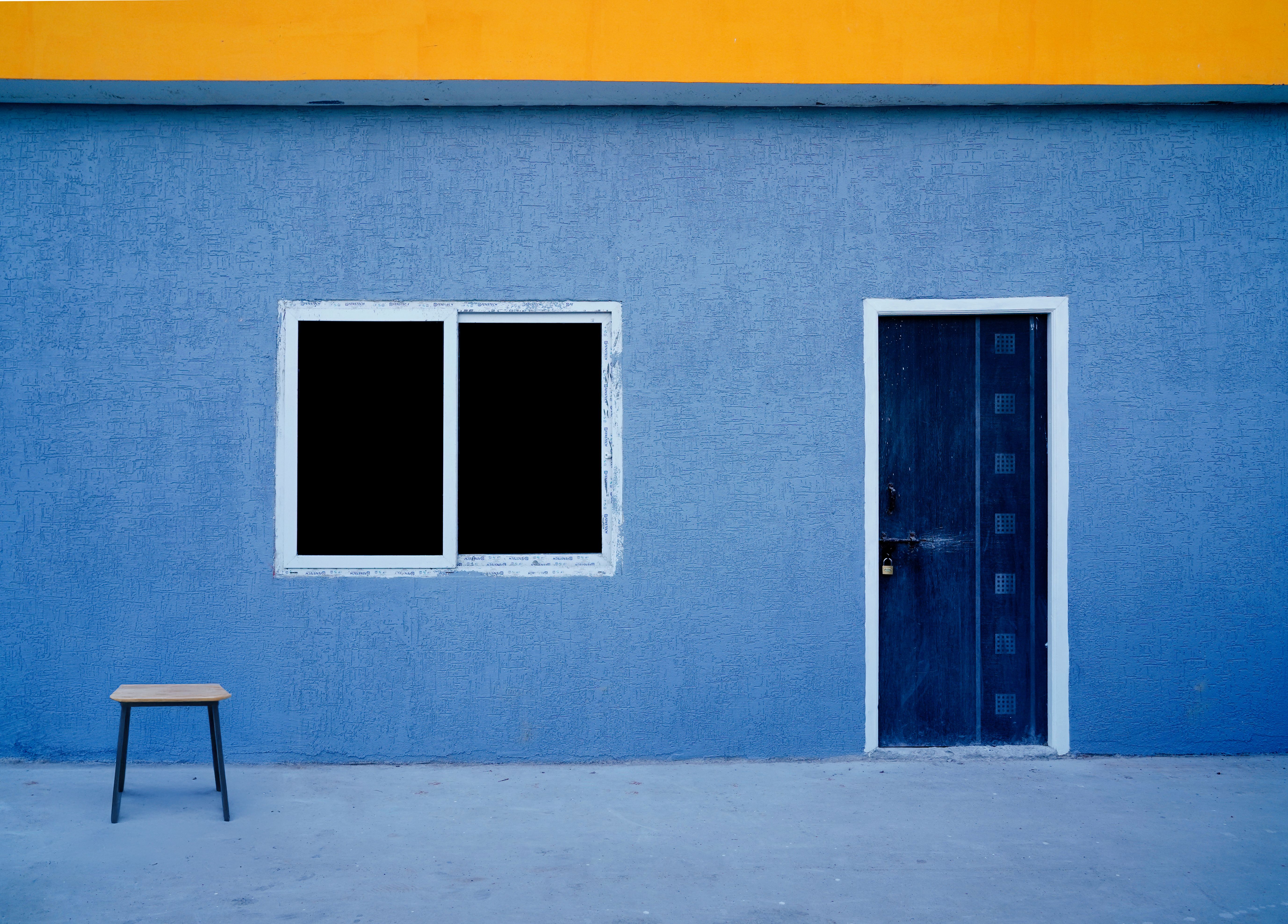 A minimalist blue wall with a window and door in Hyderabad, India
