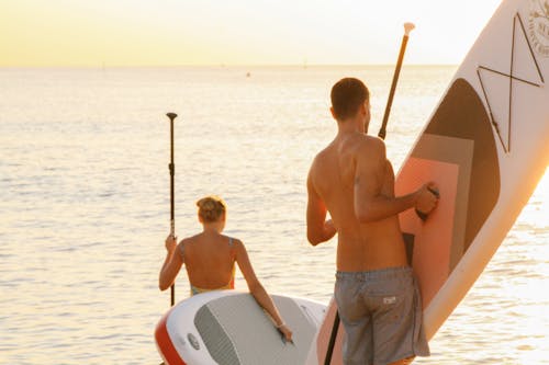 Photo of Man and Woman Holding a Paddleboard