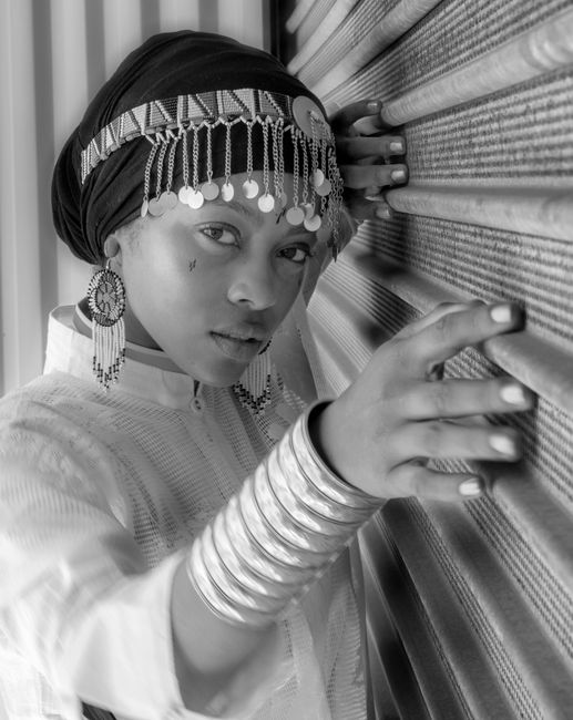 Striking black and white portrait of a woman wearing a decorative headdress and jewelry, capturing elegance and style.