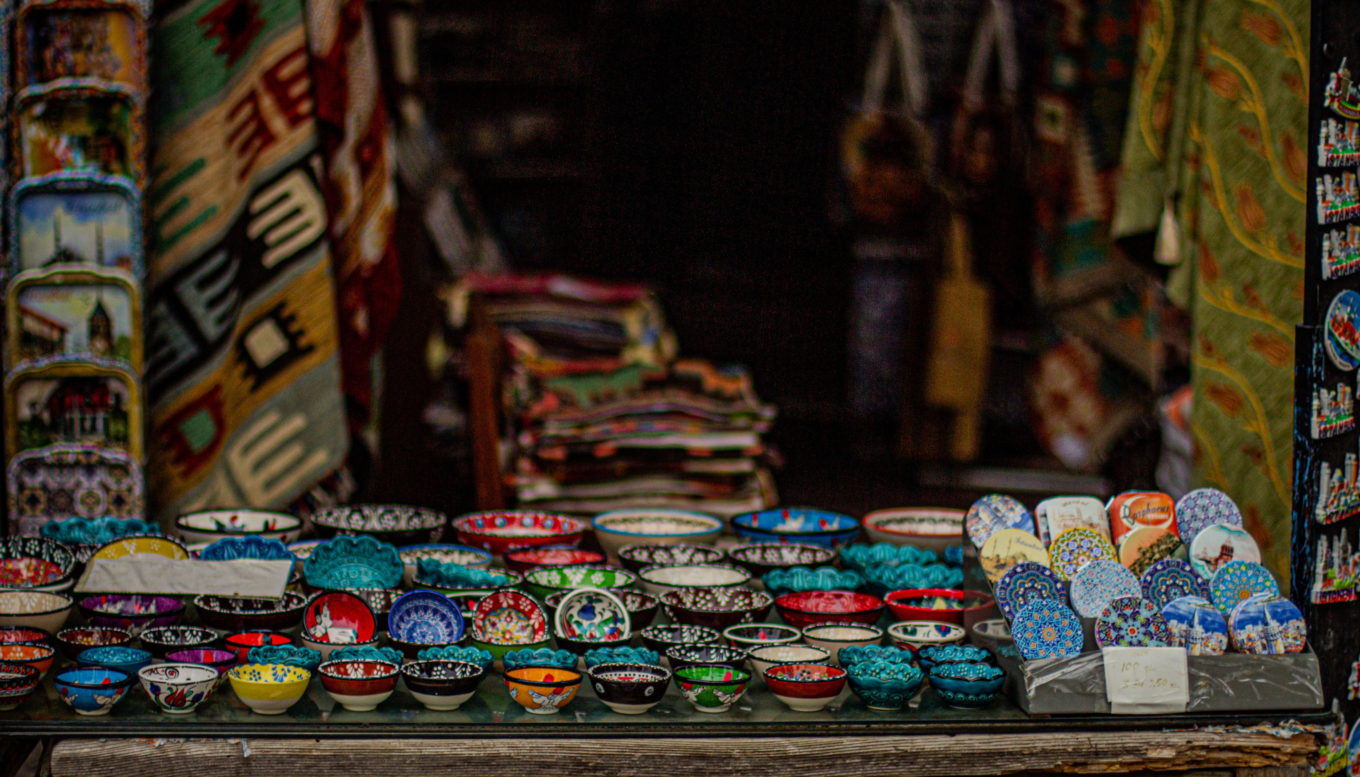 Vibrantly colored ceramic bowls displayed in a traditional artisan market setting.