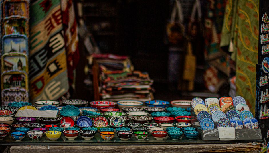 Vibrantly colored ceramic bowls displayed in a traditional artisan market setting.