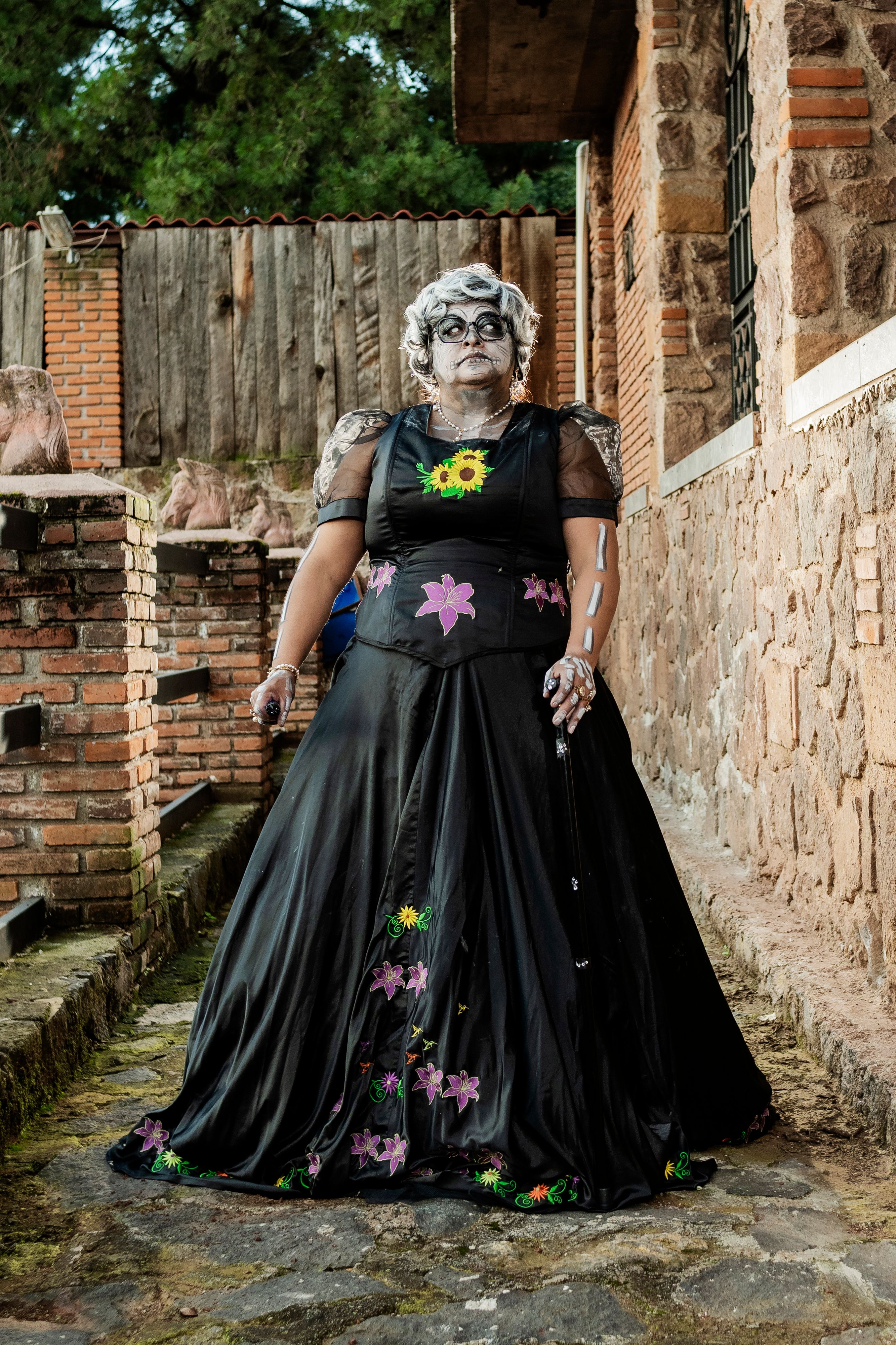 Individual in a Dia de los Muertos themed outfit outdoors.