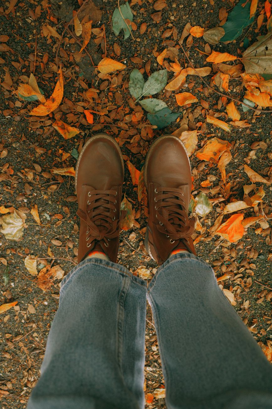 Brown boots on a bed of colorful fall leaves, capturing the essence of autumn fashion.