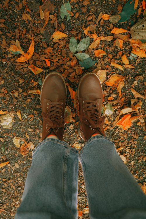 Free Brown boots on a bed of colorful fall leaves, capturing the essence of autumn fashion. Stock Photo