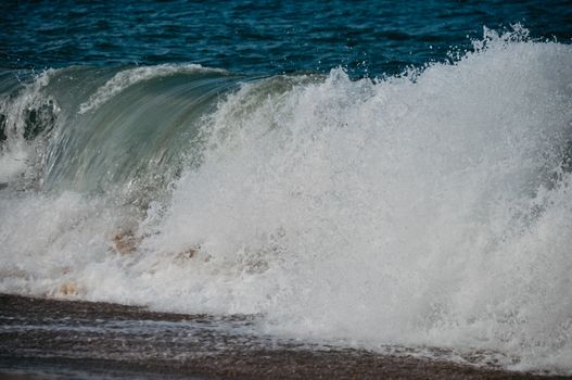Captivating image of a wave breaking on a sandy shore, showcasing the ocean's force and beauty.