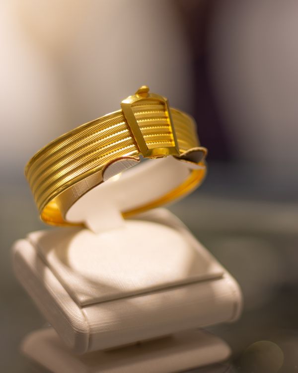 Gold bracelet displayed on a white stand — photo by Vedat Kandemir on Pexels