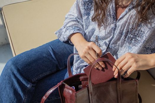 A woman looks through her handbag while sitting on an outdoor sofa in Istanbul, Türkiye.
