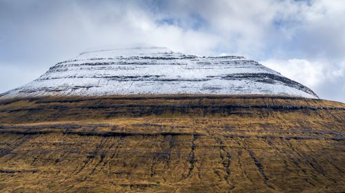 Free Breathtaking view of a snow-capped mountain and mossy cliffs under a cloudy sky in the Faroe Islands. Stock Photo