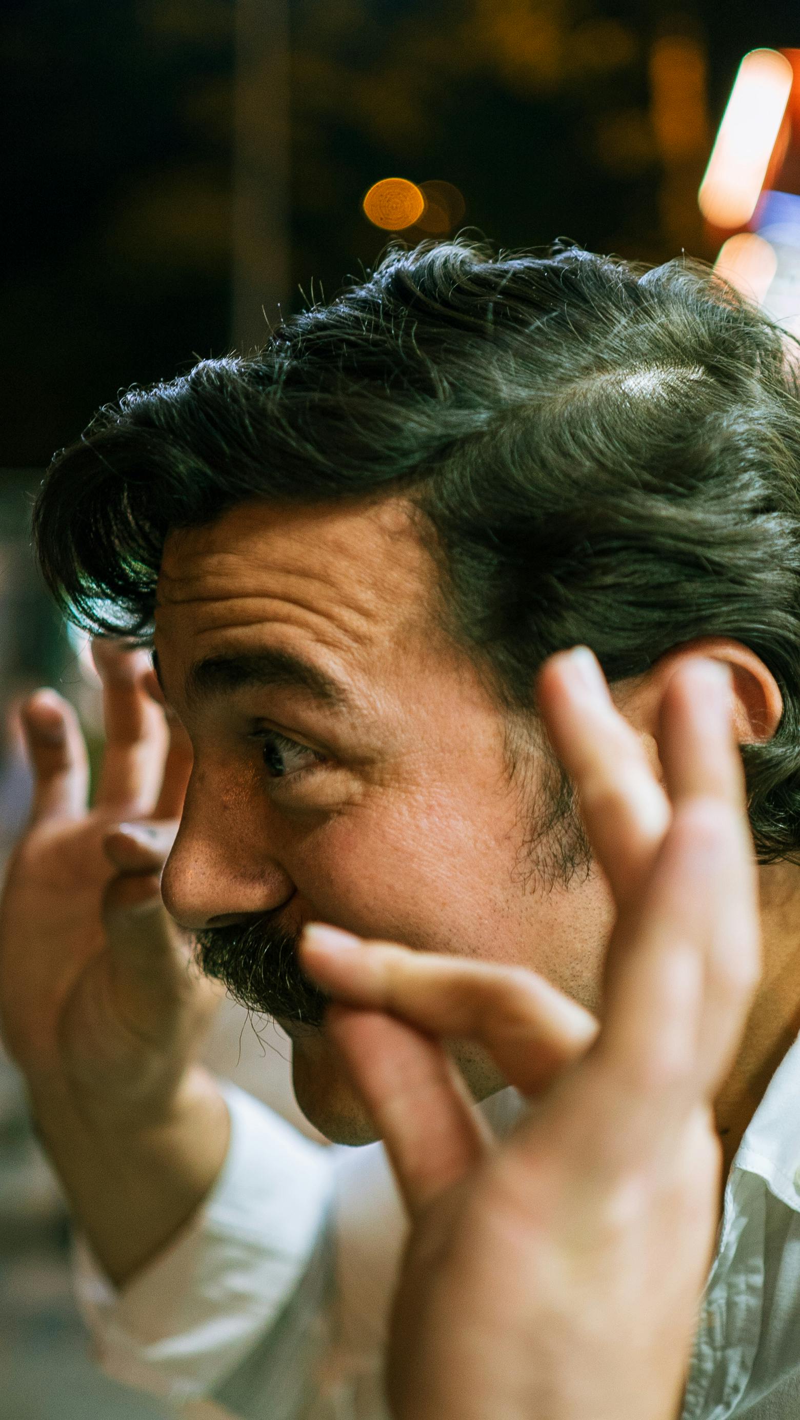 Caucasian man with mustache enthusiastically gesturing with hands indoors.