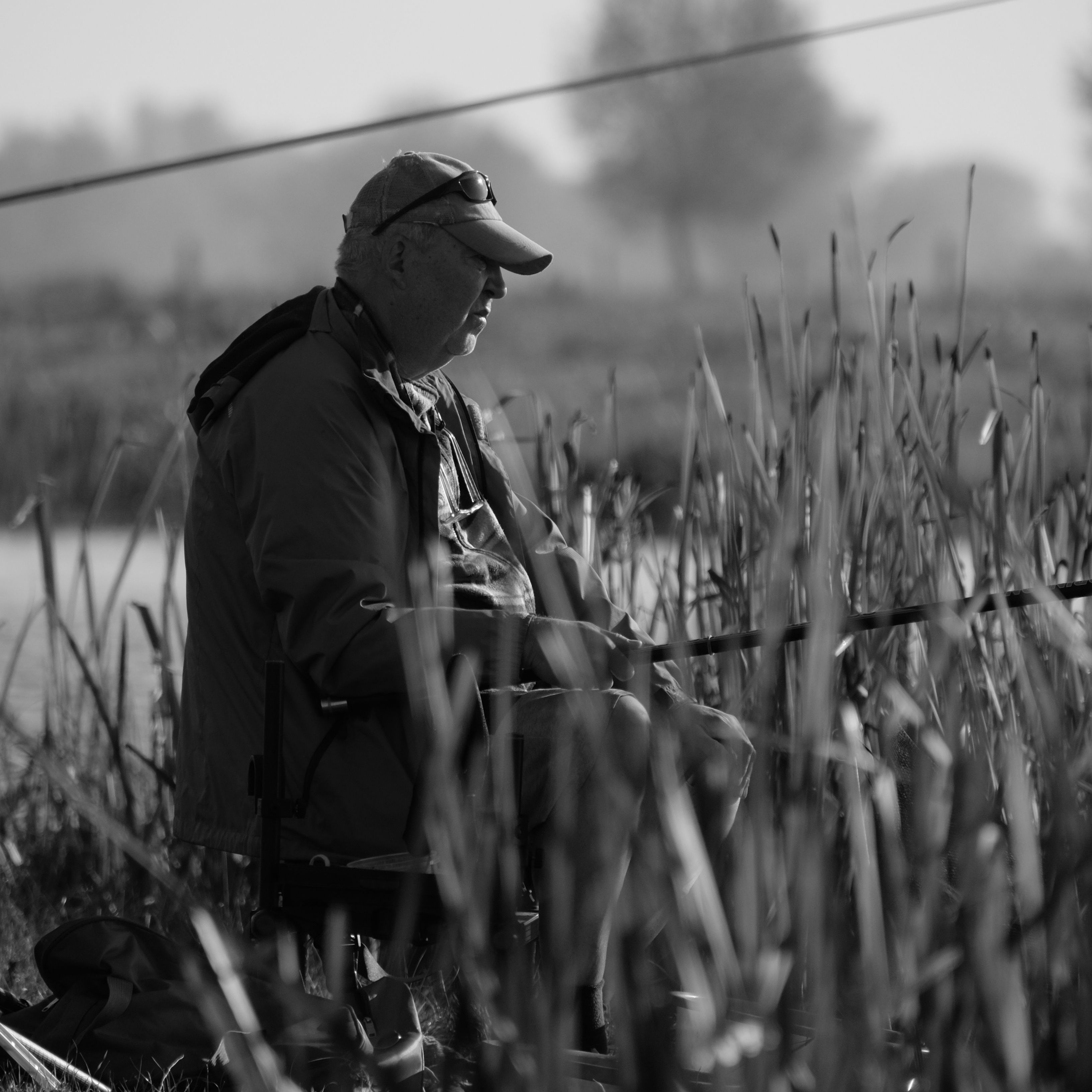 Black and White Man Fishing in Reeds at the Lake