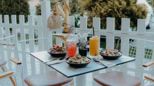 Free A cozy outdoor cafe table with colorful salads, refreshing drinks, and a serene garden view. Stock Photo