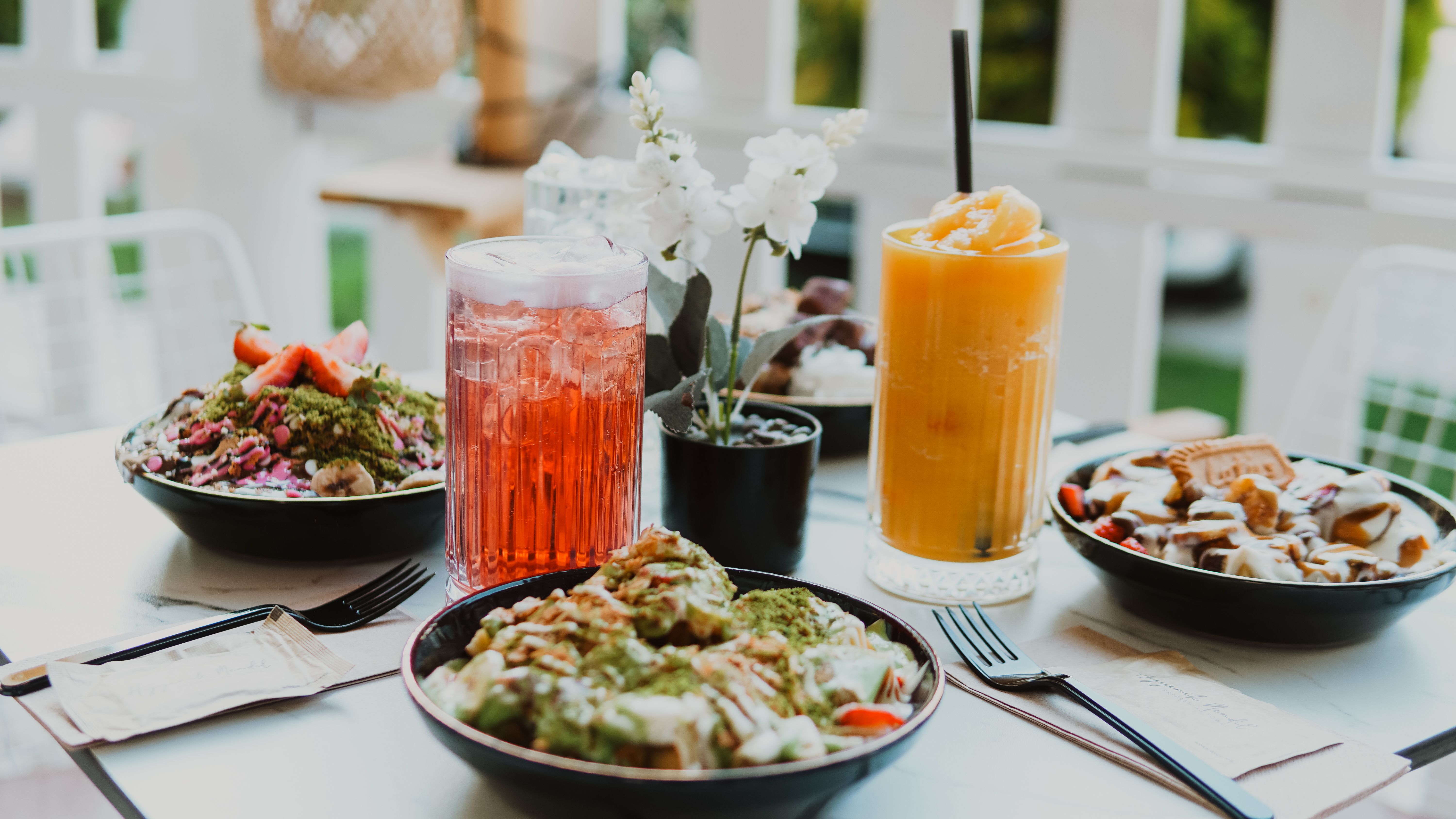 A vibrant spread of healthy dishes and refreshing drinks on an outdoor table setting.