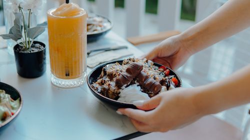 Free A hands placing a dessert bowl with chocolate and strawberries beside a refreshing orange drink on a table. Stock Photo