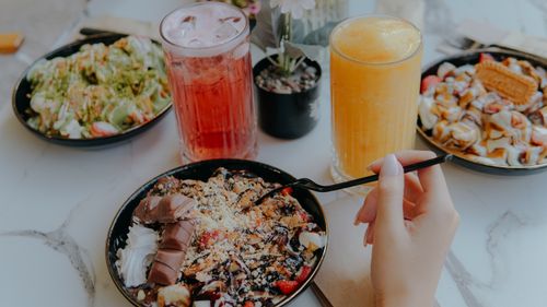 Free A top view of various desserts and vibrant drinks on a marble table, offering a cozy dining experience. Stock Photo