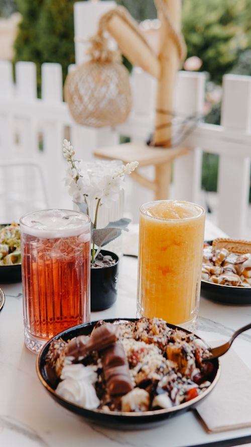 Free A vibrant outdoor breakfast table featuring fresh juices and fruit bowls, ideal for a summer morning. Stock Photo