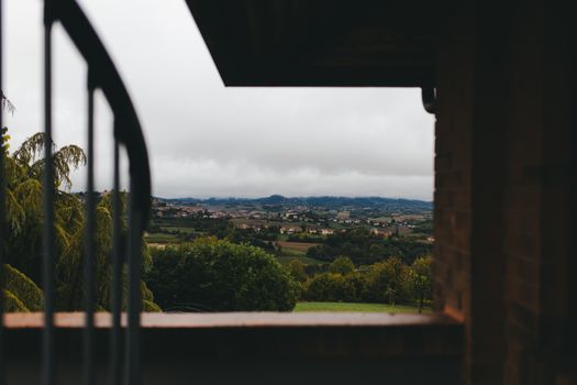 Serene view of a picturesque countryside framed by a balcony on an overcast day.