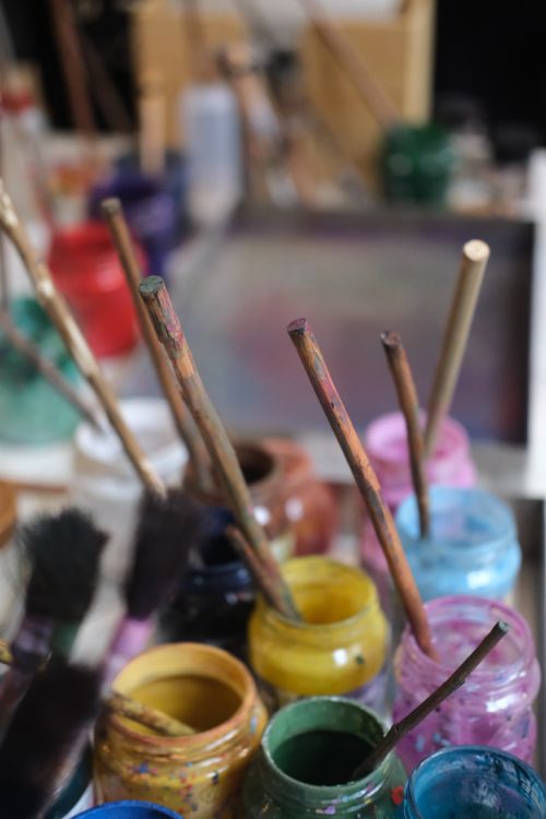 Free Vibrant collection of paint jars and brushes in a creative art studio setting. Stock Photo