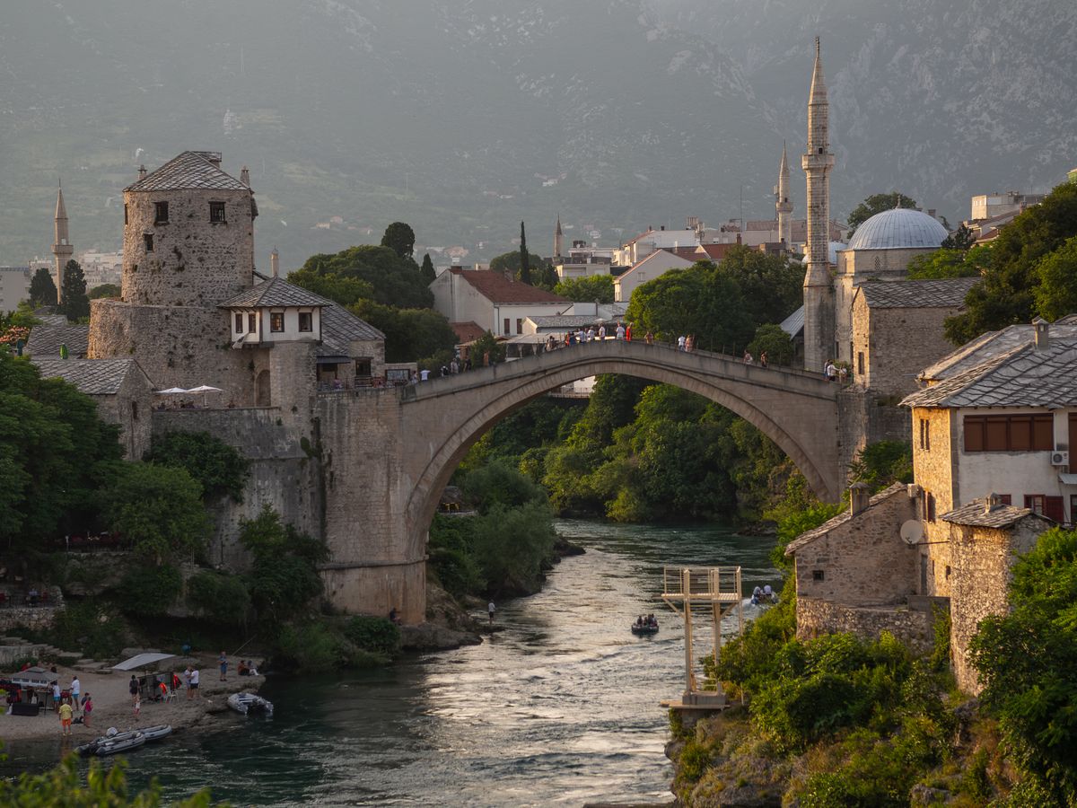 Podul Vechi din Mostar la apus, cu arcul lui de piatră deasupra Neretvei în lumină caldă