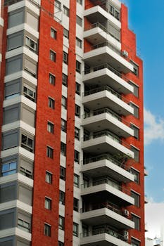 High-rise red brick apartment building with balconies in an urban setting.