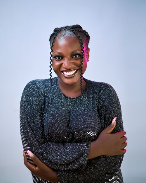 Free Cheerful woman in a glittery top smiling confidently with braided hair. Stock Photo