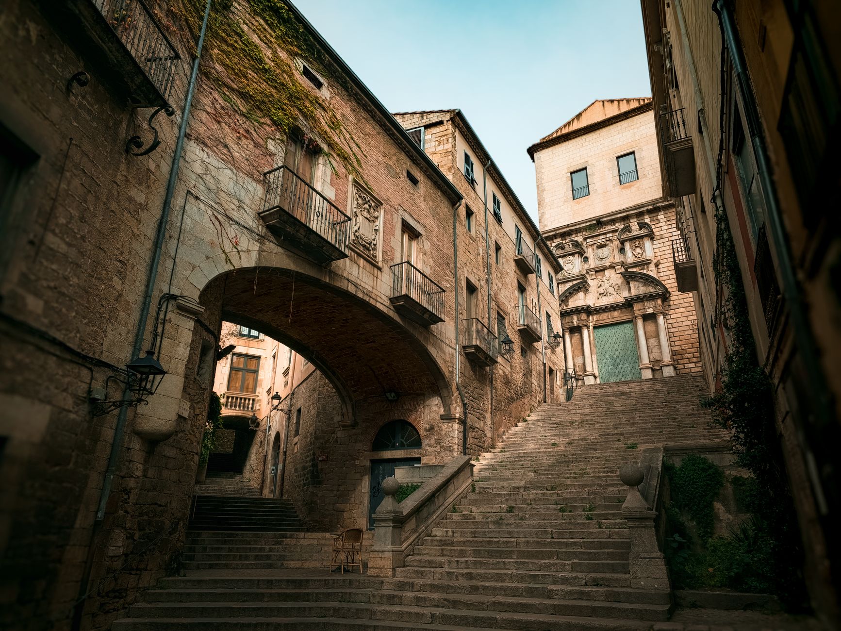 Narrow stone-paved lane with stone archway in El Call, Girona's medieval Jewish quarter