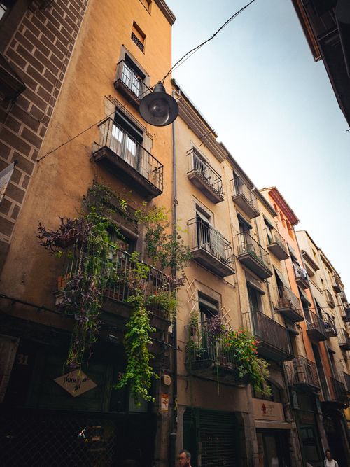 Free A picturesque street in Girona, Catalonia, showcasing historic buildings and balconies adorned with greenery. Stock Photo