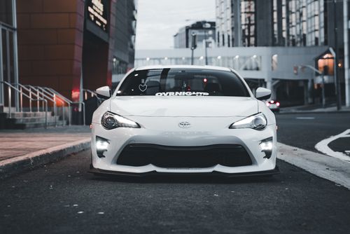 Free A modern white sports car parked on a city street, showcasing urban automotive style. Stock Photo