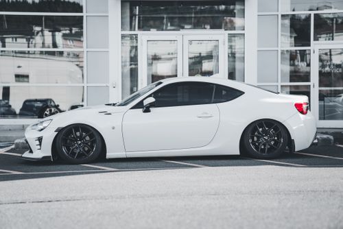 Free Side view of a modern white sports car in front of a glass building. Stock Photo