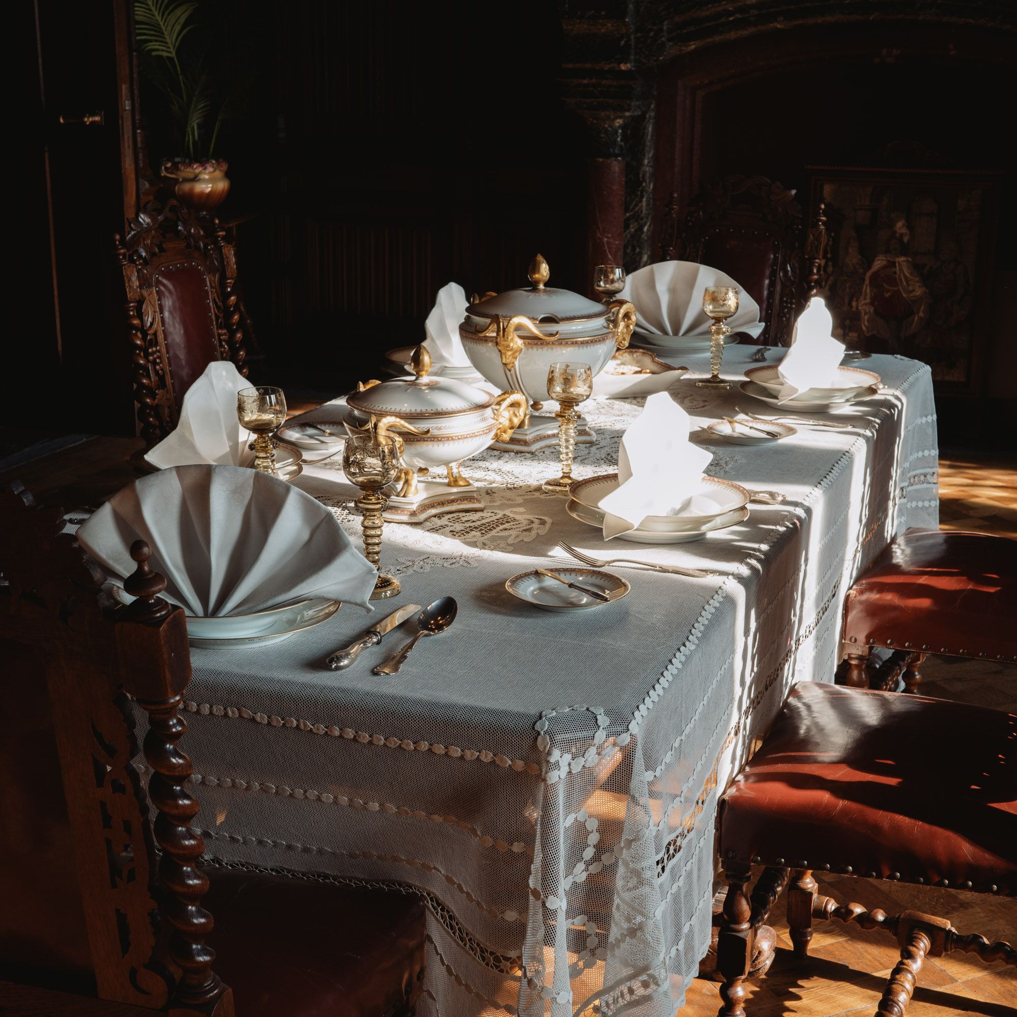 A beautifully set vintage dining table with ornate tableware and warm lighting.