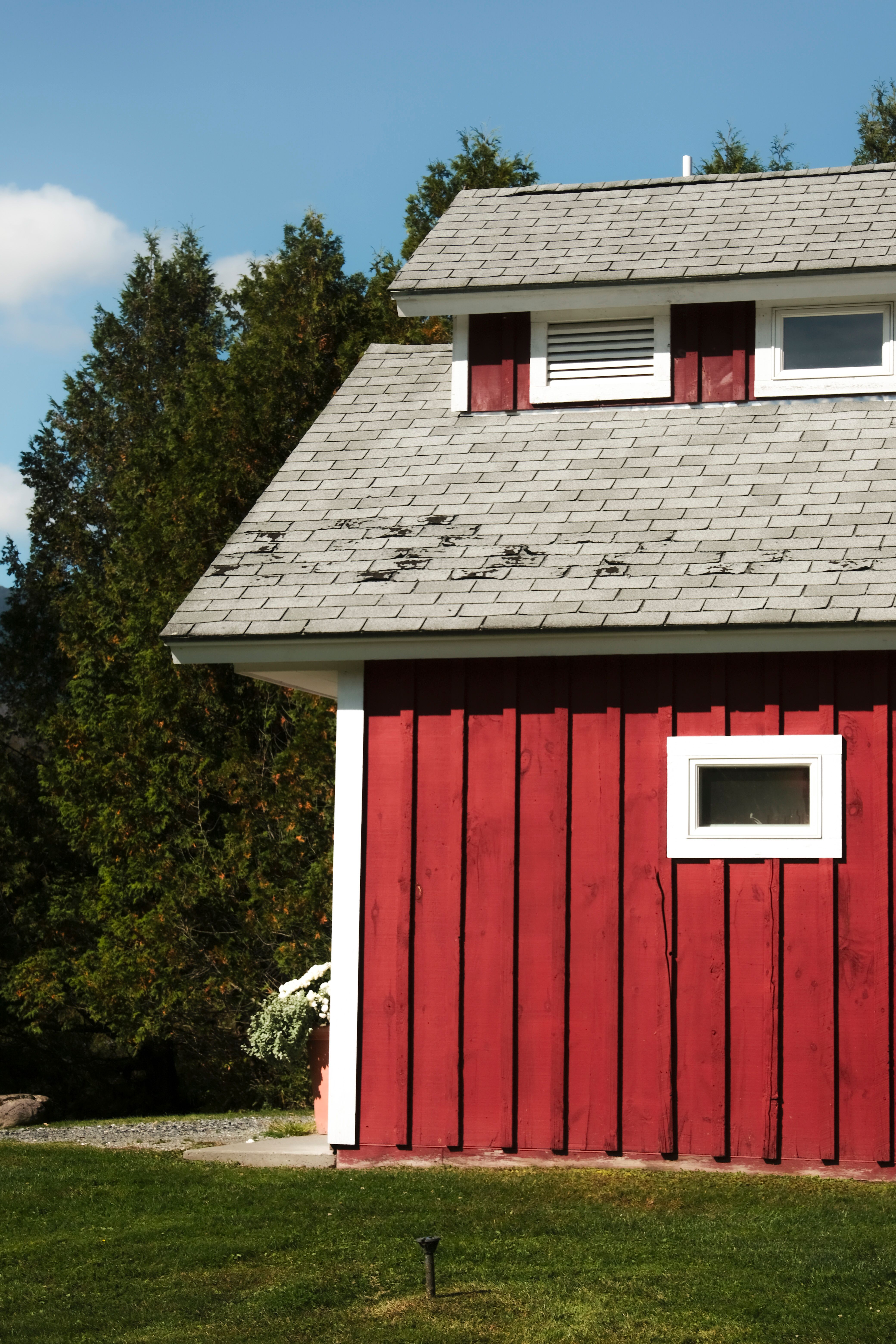 Charming red wooden barn facade with a clear blue sky backdrop.