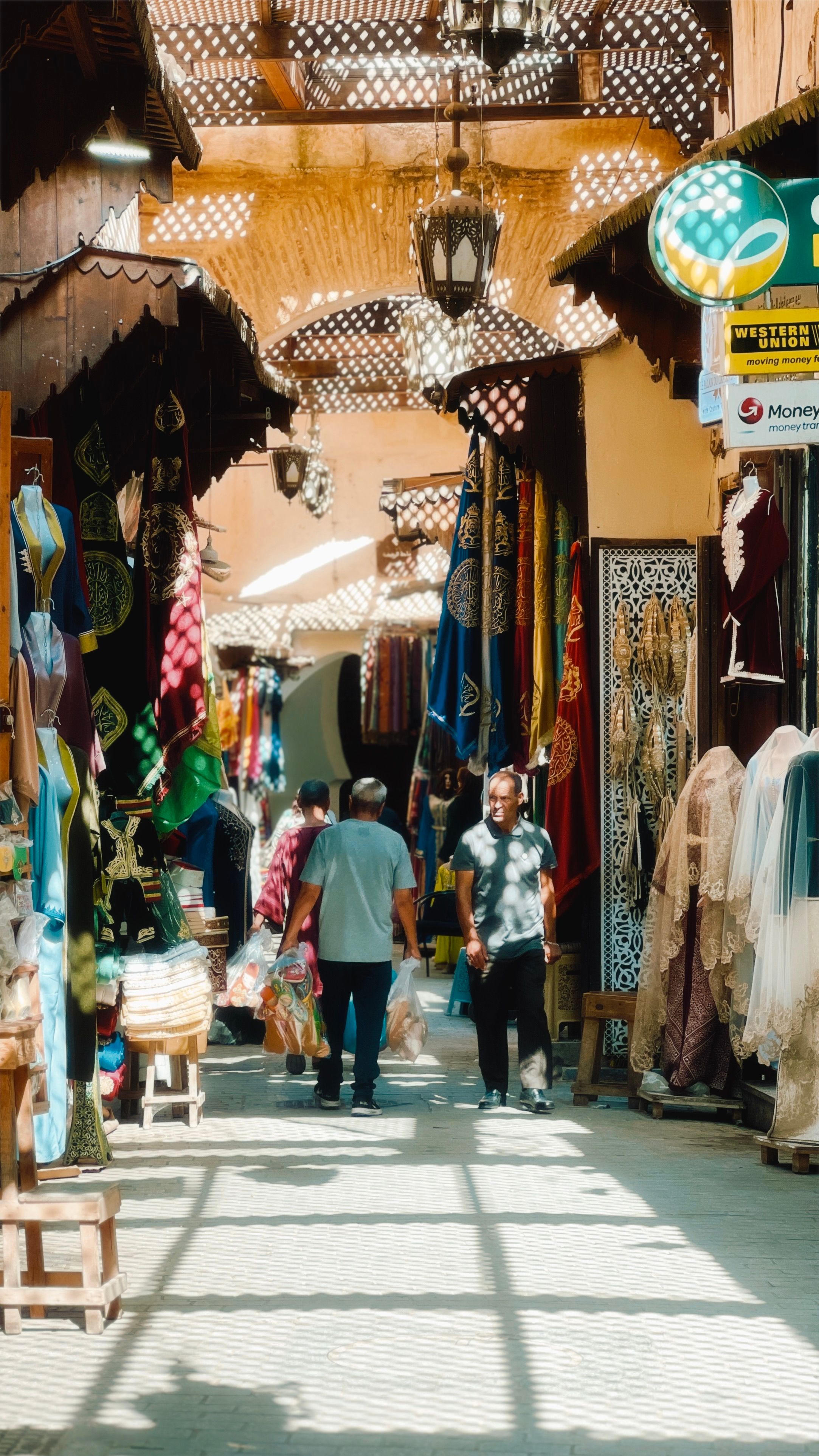 Best Things to Do in Djerba on a Short Trip 2 Vibrant marketplace scene in Fes, Morocco with locals walking among colorful textiles and goods.