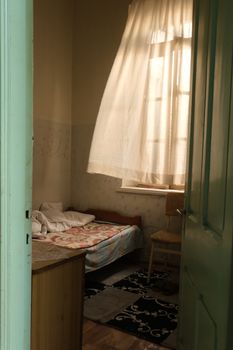 A warm and inviting bedroom with natural light filtering through curtains and an open doorway.