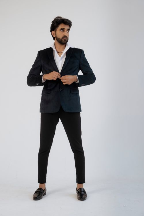 Free Man in black suit adjusts collar against a white studio backdrop, exuding sophistication. Stock Photo