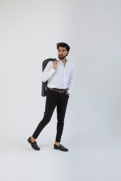 Free Fashionable man posing in white shirt and black trousers with confident style. Stock Photo