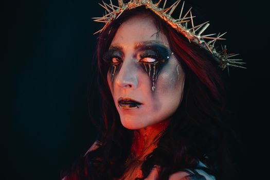 Captivating gothic portrait of a woman with artistic makeup and a thorn crown, dramatic lighting.