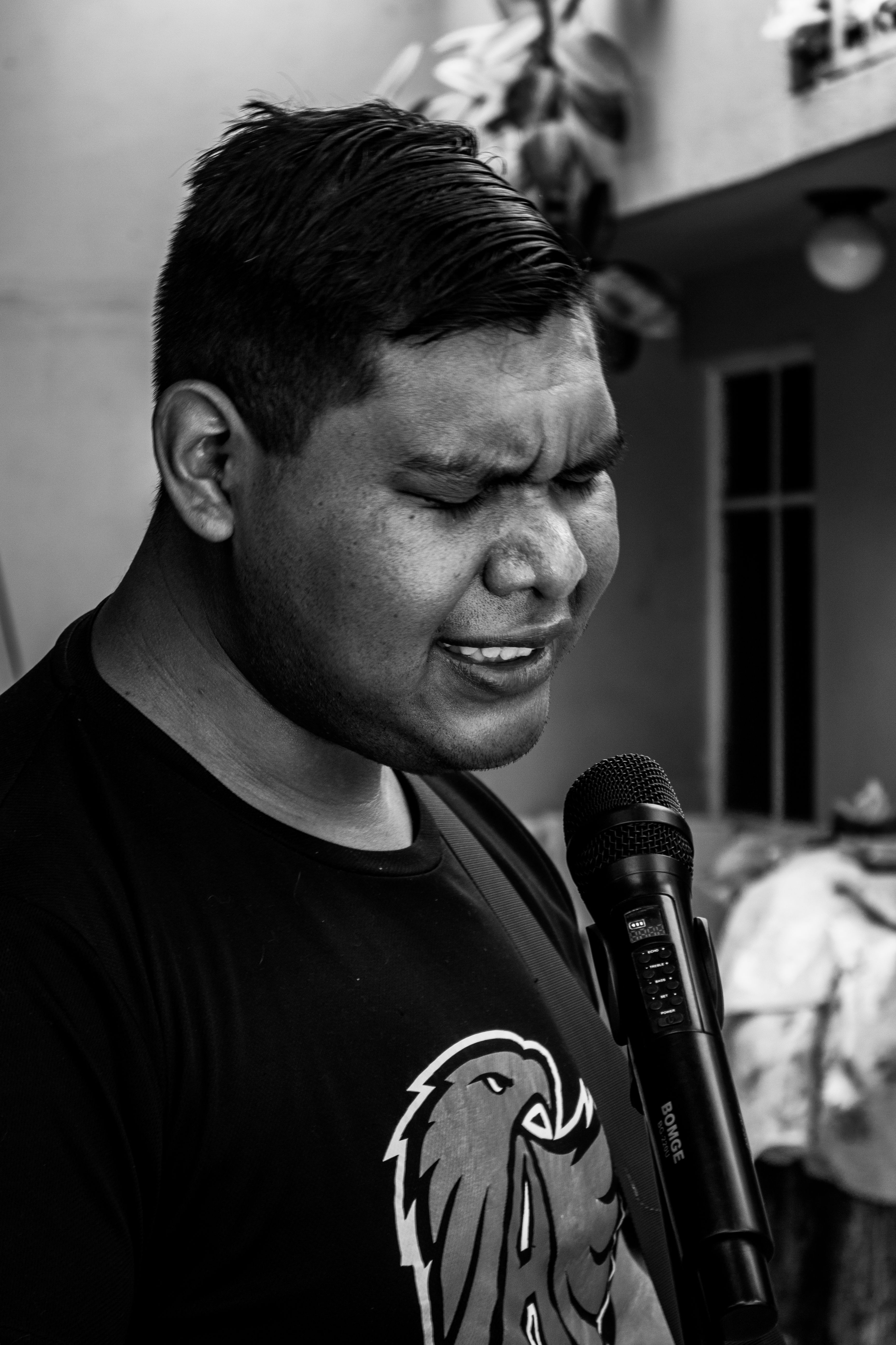 A compelling black and white portrait of a singer passionately performing outdoors into a microphone.