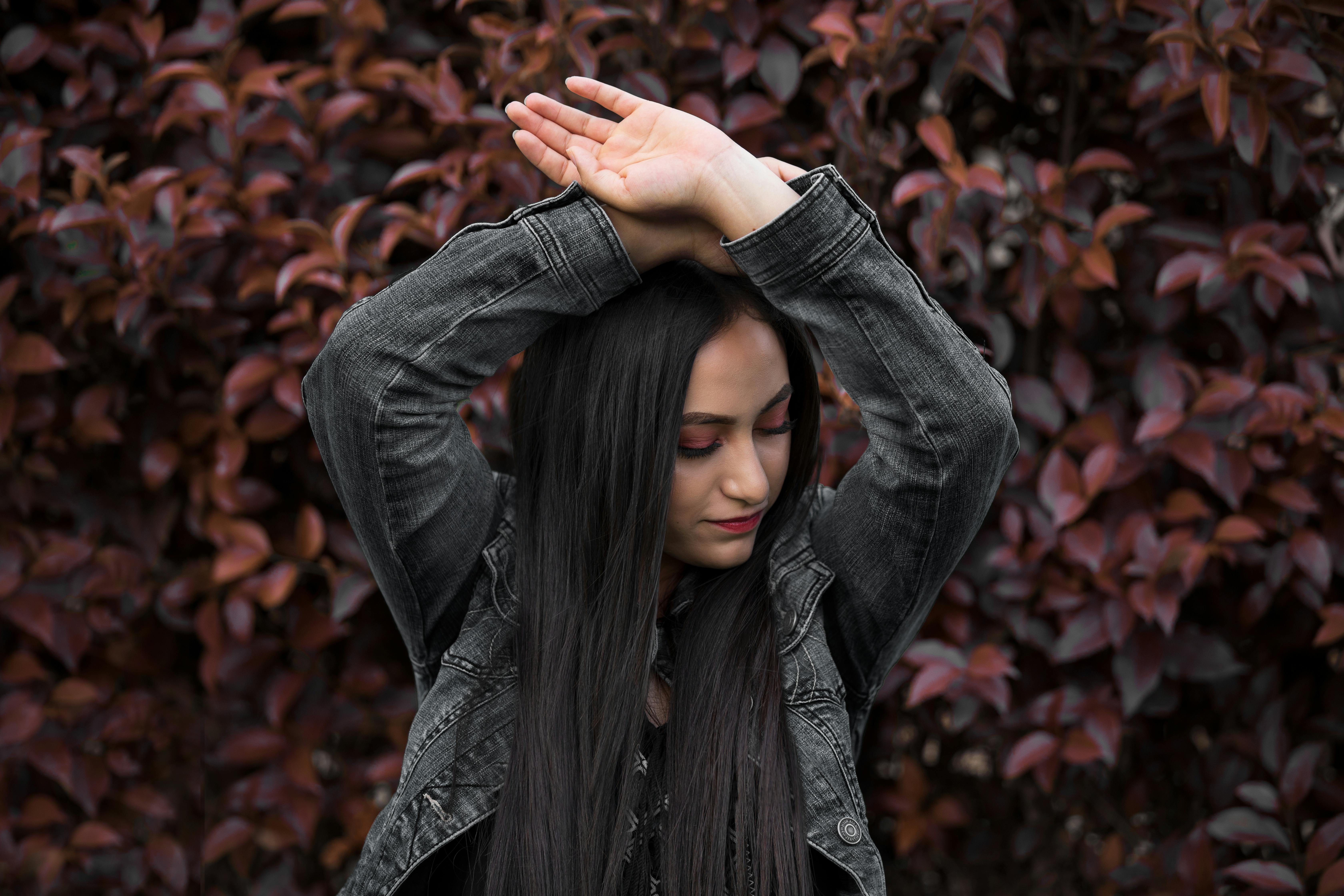 一位留着深色长发、穿着牛仔夹克的女性在墨西哥户外充满活力的绿叶背景下摆姿势