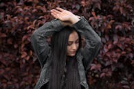 一位留着深色长发、穿着牛仔夹克的女性在墨西哥户外充满活力的绿叶背景下摆姿势