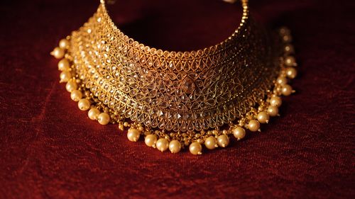 Free Elegant gold necklace with pearls on a rich red background, showcasing fine craftsmanship. Stock Photo