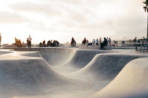 Free Skateboarders and onlookers enjoy a sunny day at an outdoor skatepark, capturing the vibrant community atmosphere. Stock Photo
