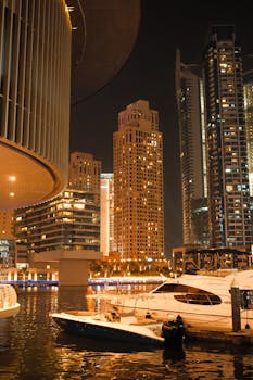 Captivating view of Dubai Marina at night with luxury yachts and stunning skyscrapers.