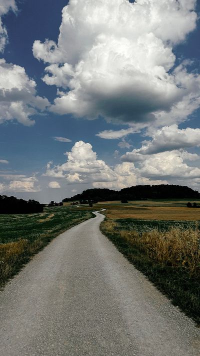 Meadow path under tall clouds by Elody on Pexels