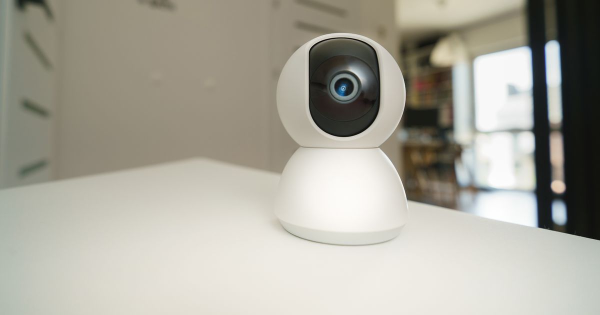 A white baby monitor camera on a table in a bright room