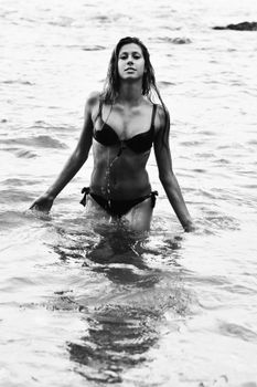 Striking black and white portrait of a woman emerging from the ocean.