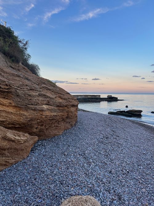 Free Beautiful rocky beach at sunrise in Odessa, Ukraine with calm sea and clear sky, perfect for tranquility seekers. Stock Photo