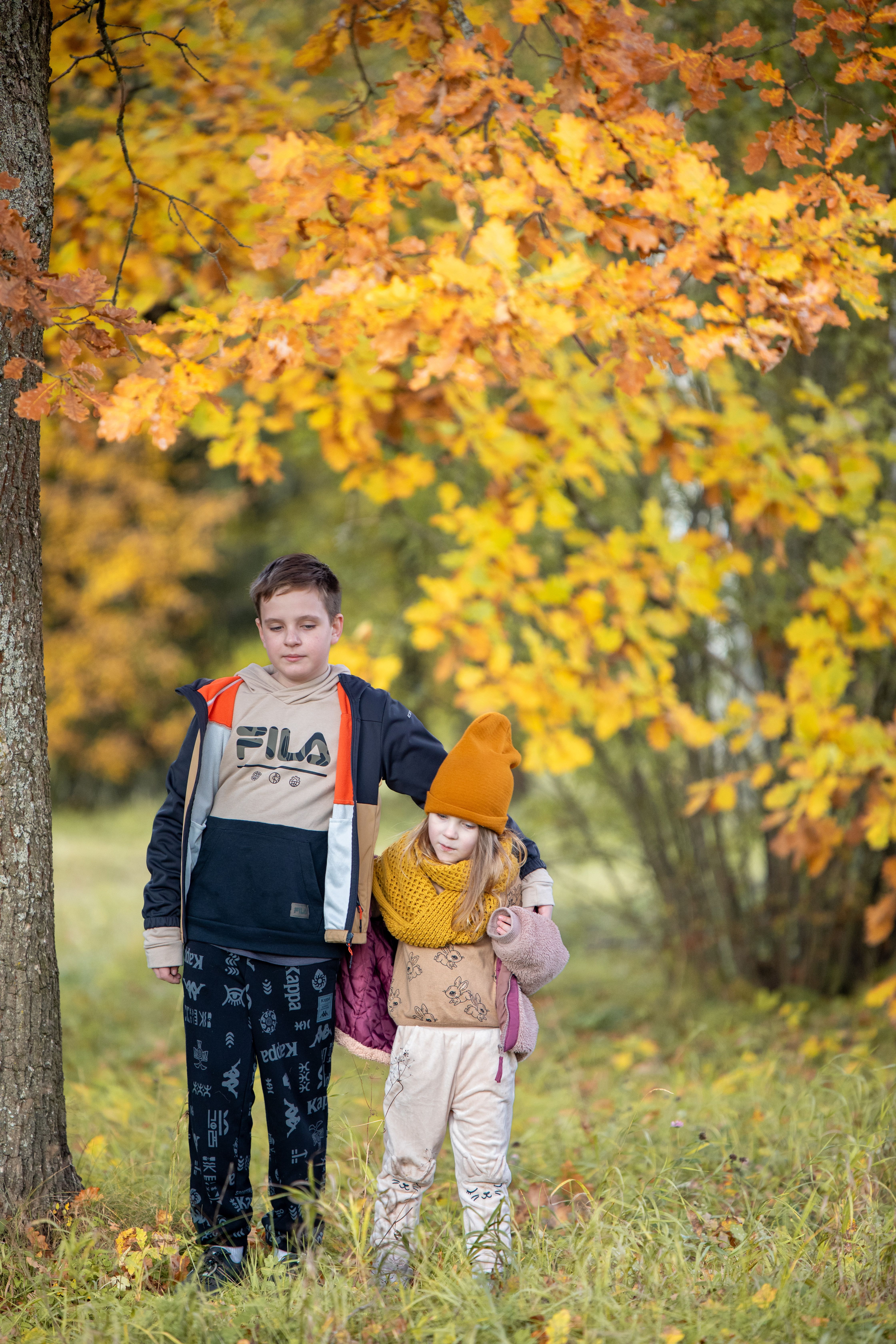 Two children enjoying a peaceful autumn day surrounded by colorful leaves in the park.