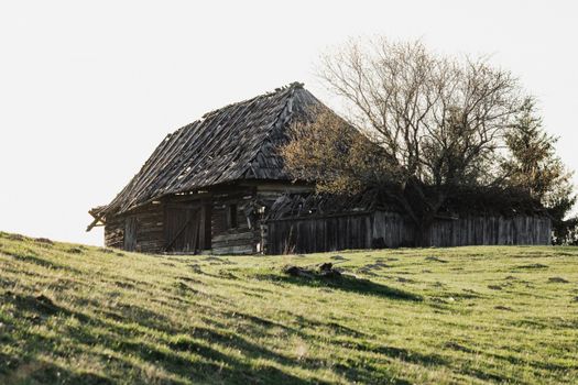 A vintage wooden barn nestled in the green hills of Lunca Ilvei, Romania, showcasing rural charm.